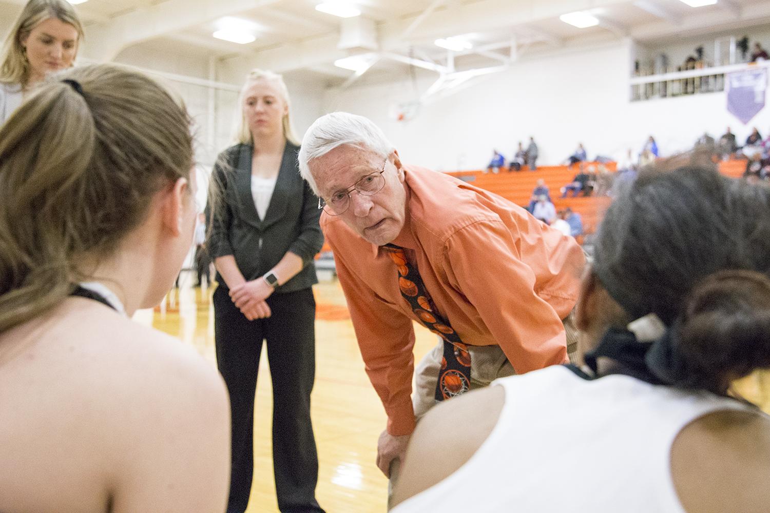 Coach Ken Swartz talks to his women's basketball team on the sidelines of a basketball game